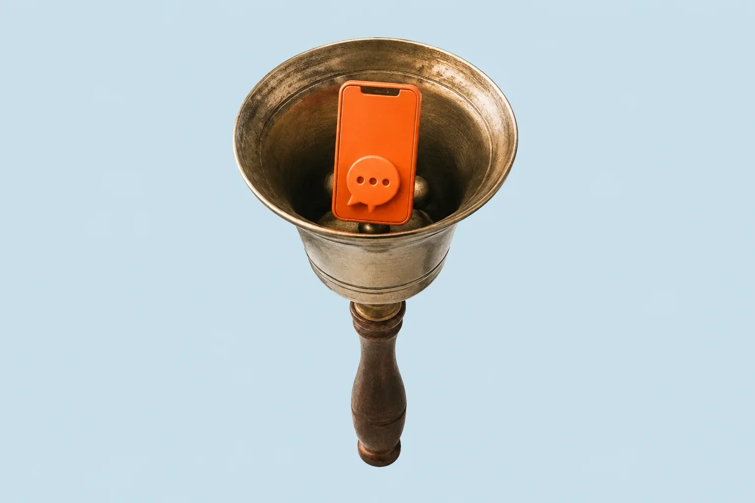 A brass hand bell held upside down with an orange phone showing a speech bubble resting inside it, on a pale blue background.